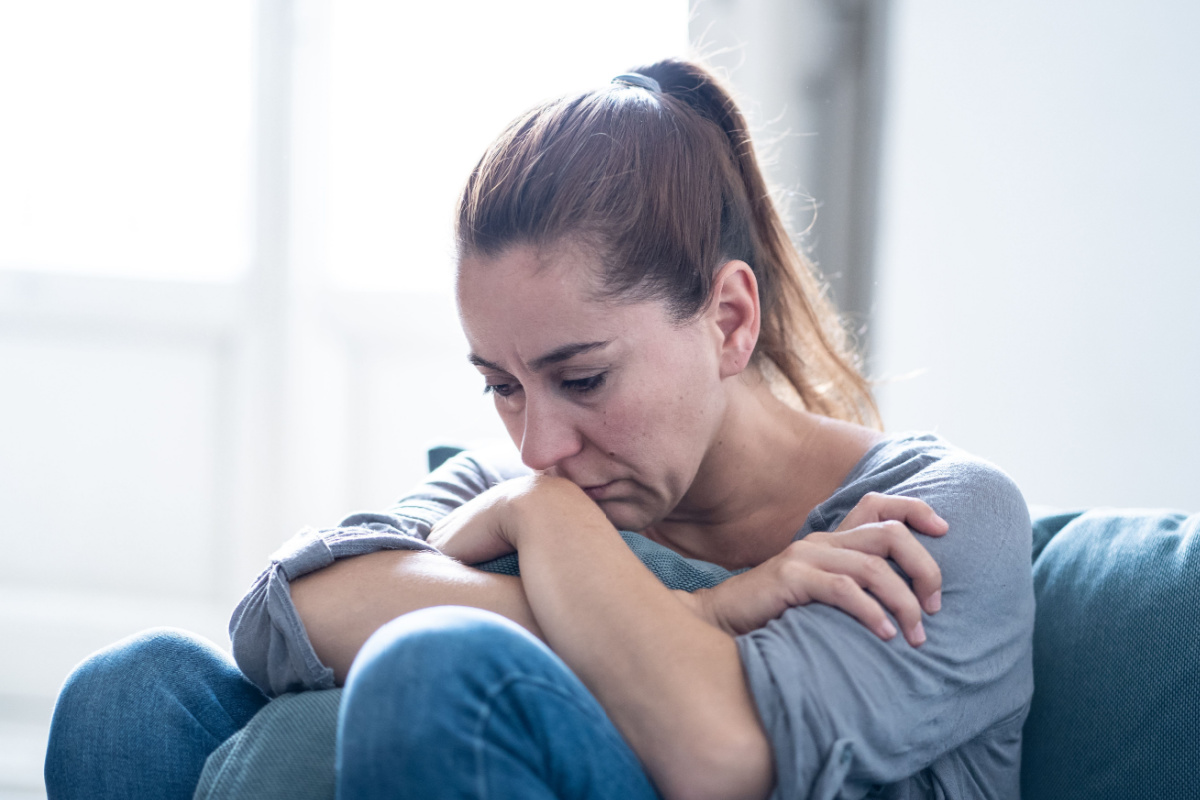 Latin woman sitting on couch depressed