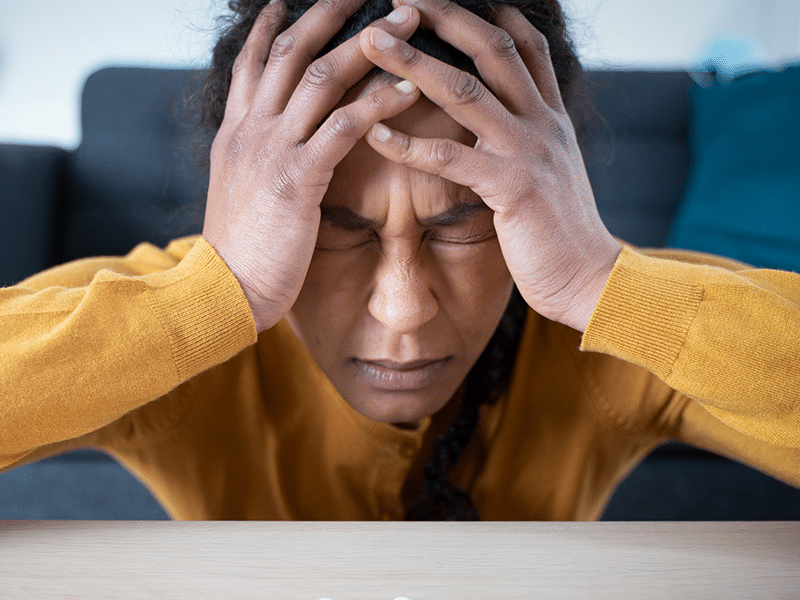 Alt Text: A woman with both hands grasping her head, symbolizing the effects of benzodiazepine addiction.