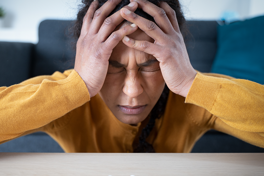 Alt Text: A woman with both hands grasping her head, symbolizing the effects of benzodiazepine addiction.