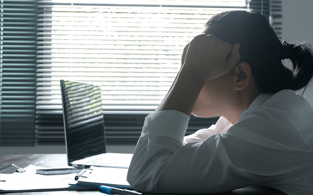 Woman near monitors with hands on temples contemplating mental health