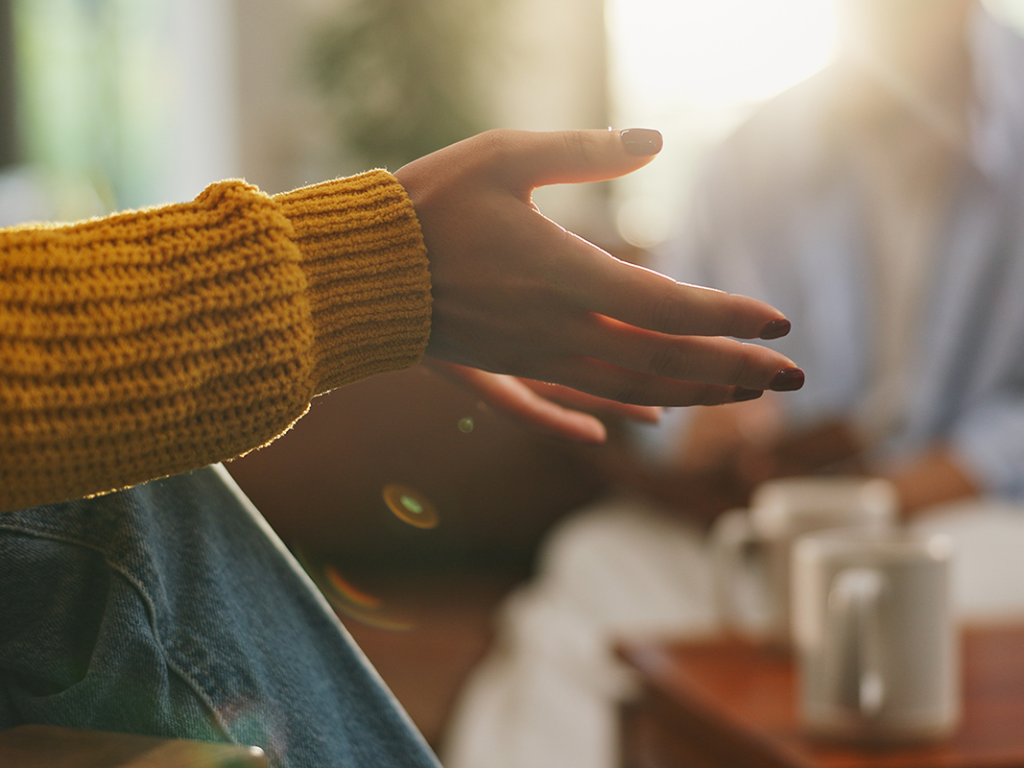 person in a yellow sweater gestures while speaking during mental health treatment